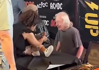 Angus Young encontra fãs após cancelamento de show e assina bebê